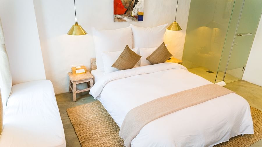 Deluxe loft room with a double bed, and a single bed side tables, and lamps hanging from the ceiling - The Nanee