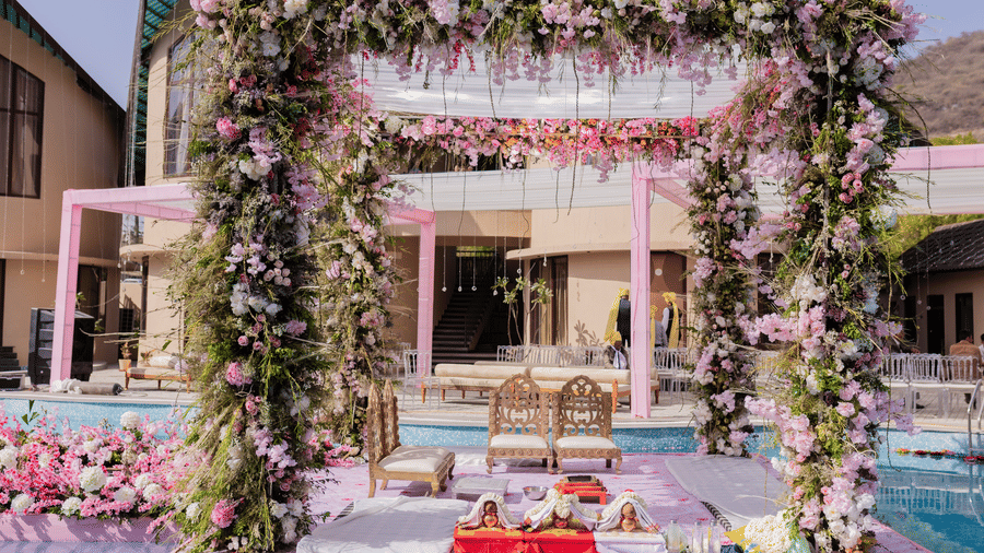 A wedding ceremony setup features a floral archway by a pool | The Qualia Resort Club & Brewery, Udaipur