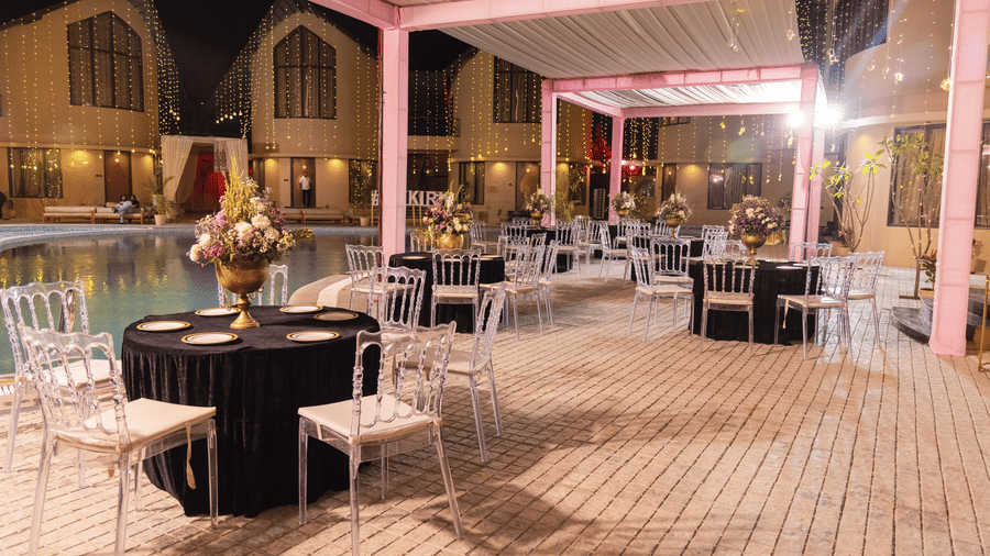 An outdoor event space is prepared with tables and chairs under a white canopy at dusk | The Qualia Resort Club & Brewery, Udaipur