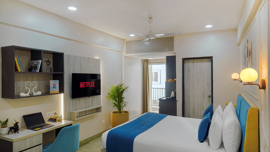 A hotel room at Urban Suites by BluSalzz, Jaipur, room view showing a desk area with a TV, a bed, and an open doorway.
