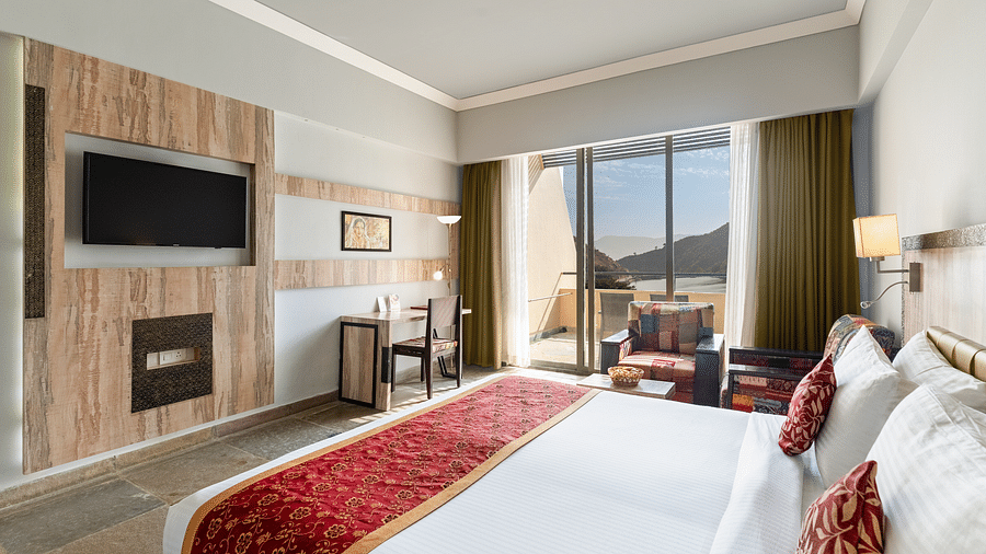 A close-up shot of a bed, opposite to it is a tv mounted on the wall - Via Lakhela Resort & Spa