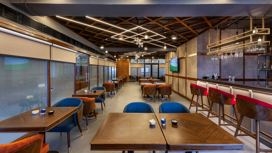 Modern restaurant with warm lighting, wood finish, and distil bar seating along glass walls.