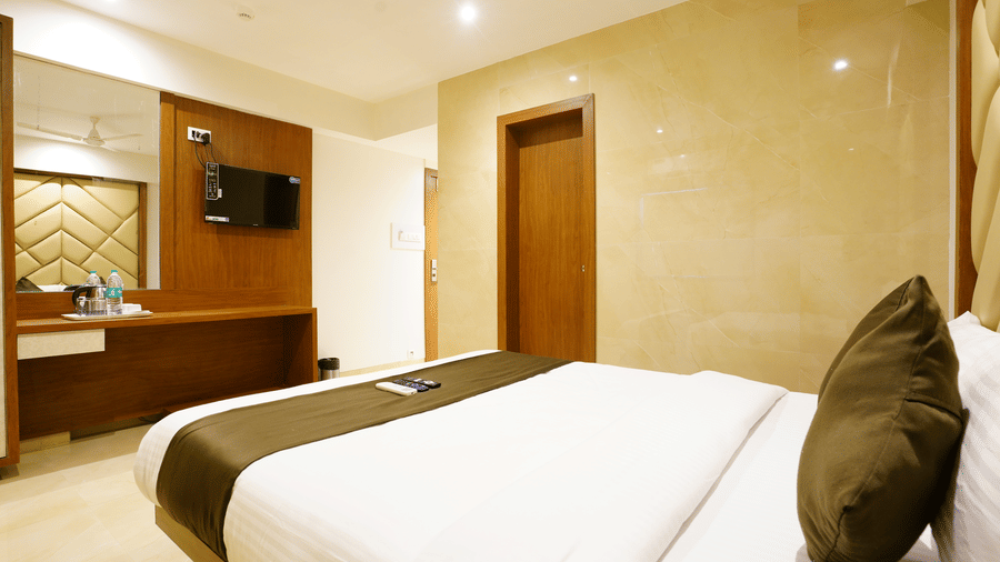 A well furnished room with a twin size bed, dressing table and a mounted T.V. at Shyanu Lords Eco Inn Airoli.