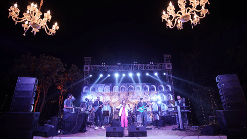 Live musical performance on an illuminated stage with chandeliers at Heritage Village Resorts & Spa, Manesar during an evening wedding.