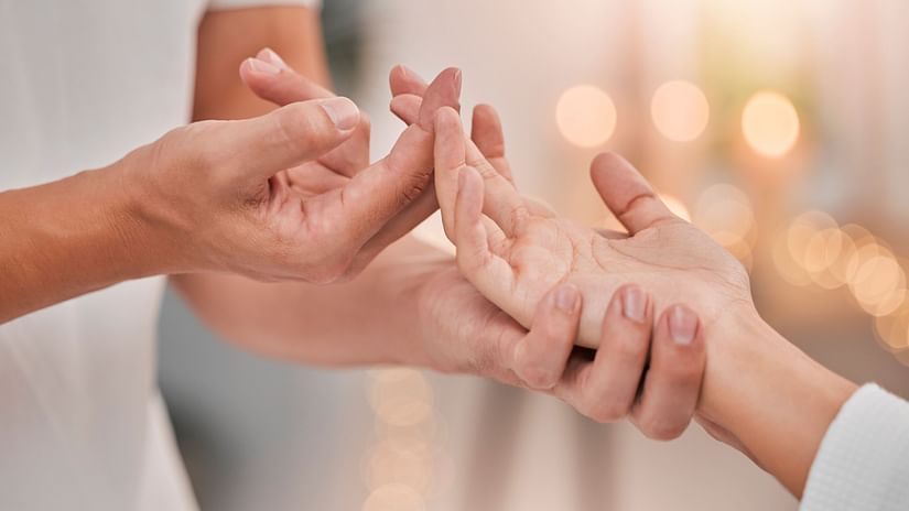 A couple gently caressing each others hand, pictured in the bokeh of the golden hour.