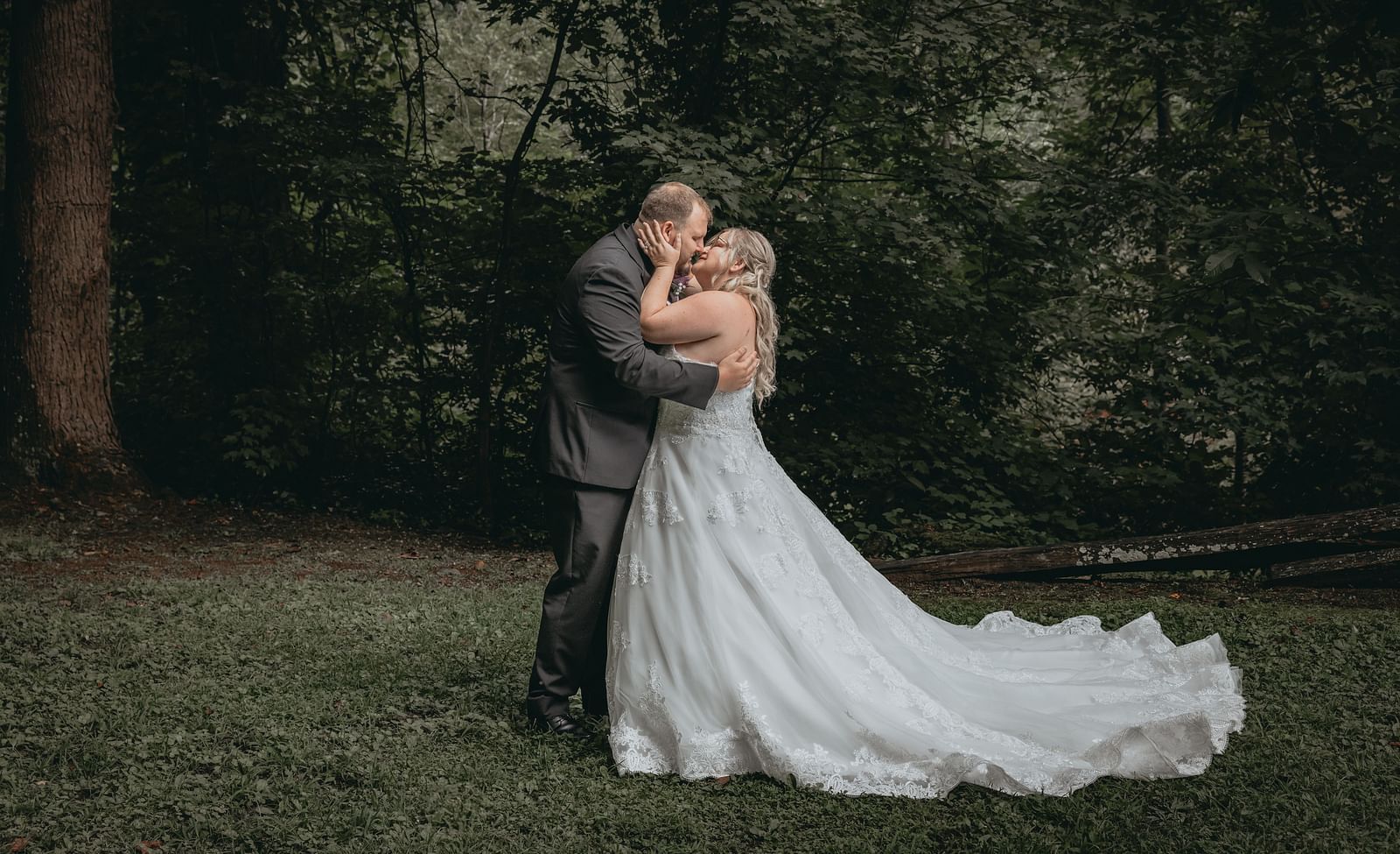 Bride and groom kissing each other in a forest covered with grass and trees near the Historic Tapoco Lodge.
