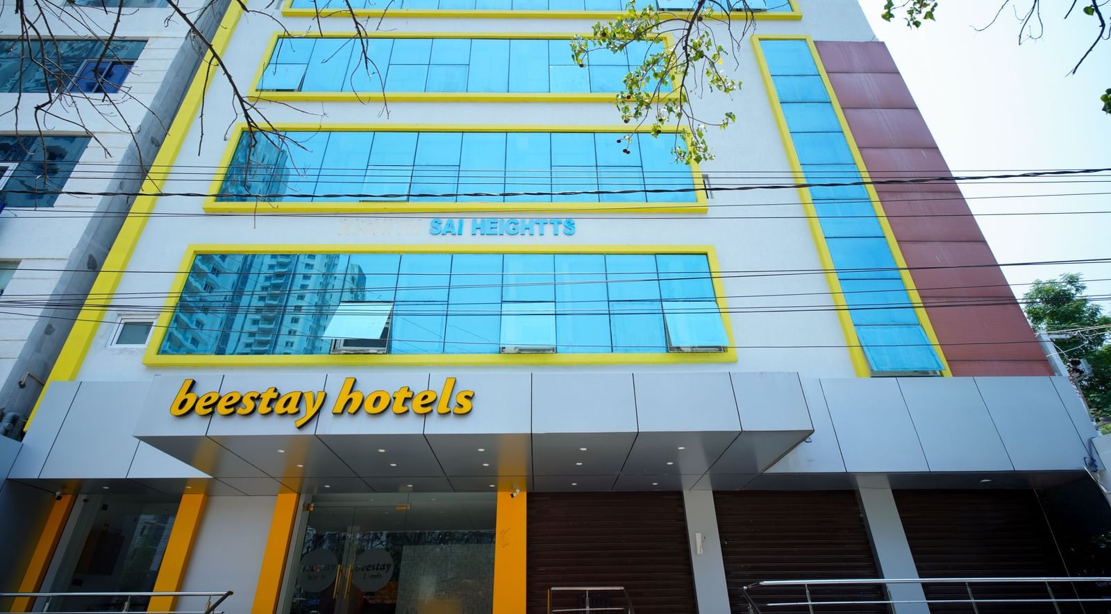 A multi-story building with blue-tinted windows and Beestays Hotels written on the facade - Beestay Hotels Financial District, Hyderabad 