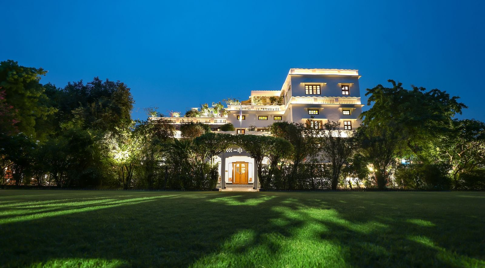 A wide view of the garden area of Saraca Hotel, Lucknow with the hotel building in the background during blue hour