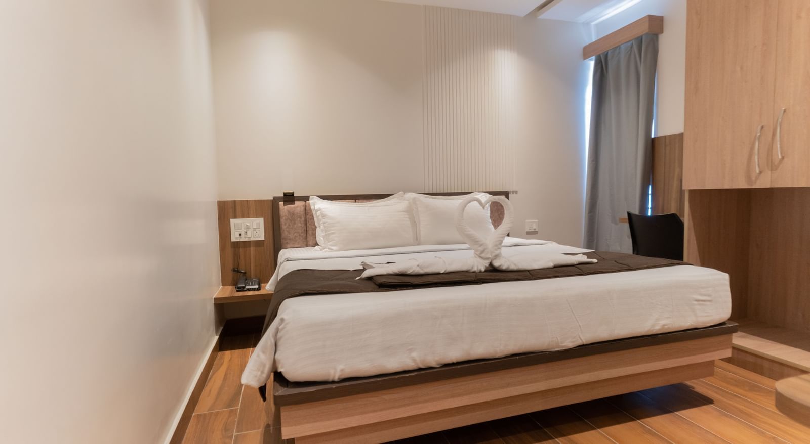 Spacious bedroom with wooden flooring and a comfortable double bed at Beestay Hotels, Rajahmundry.