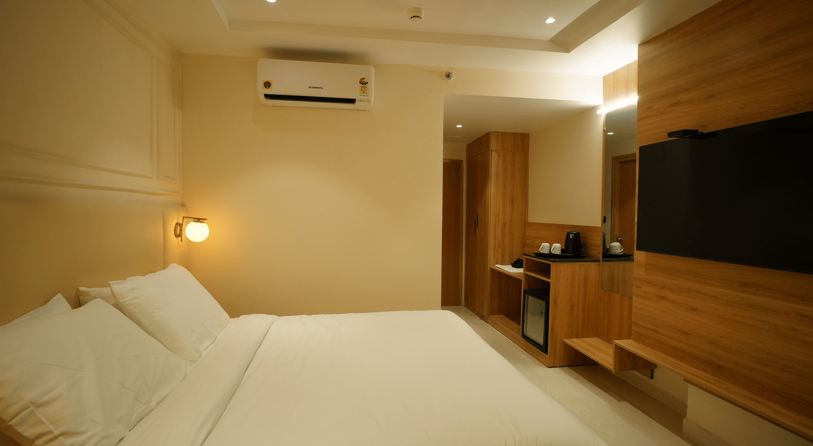  Bright room at Monday Premium, Madhapur, featuring a large bed with crisp white bedding and a wood-panelled wall with a TV.