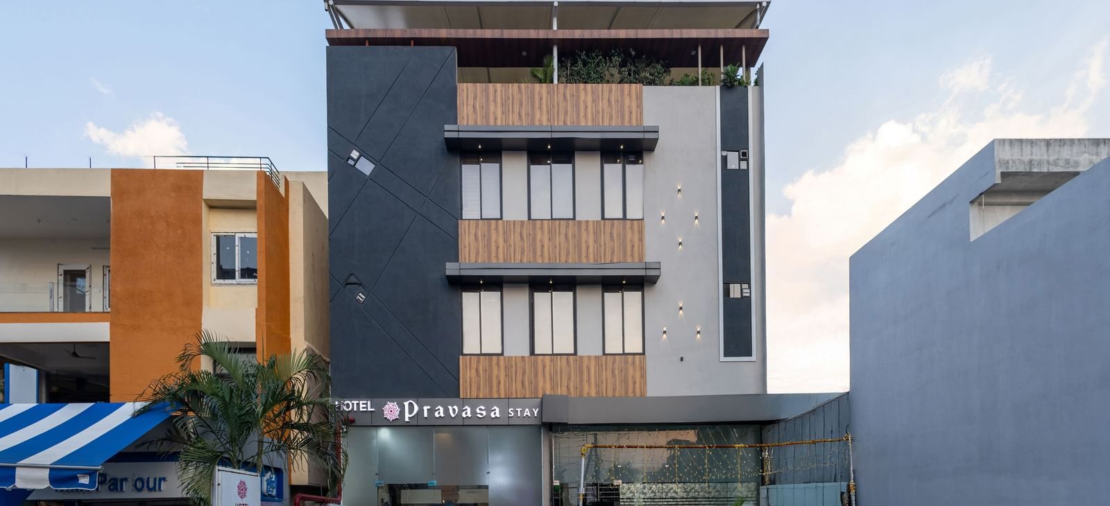 The facade of a modern multi-storey Pravasa Stay Dewas Naka, Indore under the blue sky.