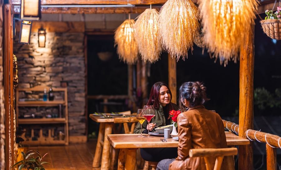 alt-text  Two women sitting across each other in our outdoor seating arrangement - The Manor Luxury Hotel, Shimla