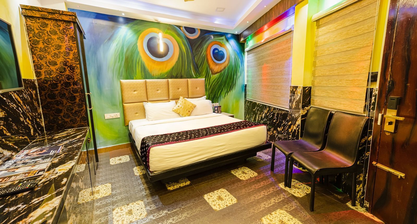 A double bed, chairs and a cupboard at the Deluxe Room at Parakkat Nature Hotel and Resorts Munnar