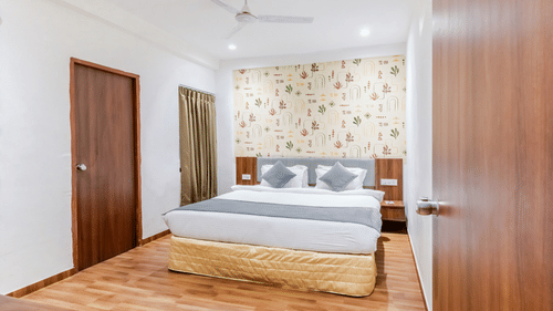 Suite at Pride Elite Wellness Resort Becharaji, Gujarat featuring a plush bed on wooden furnished floor with two nightstands on both sides