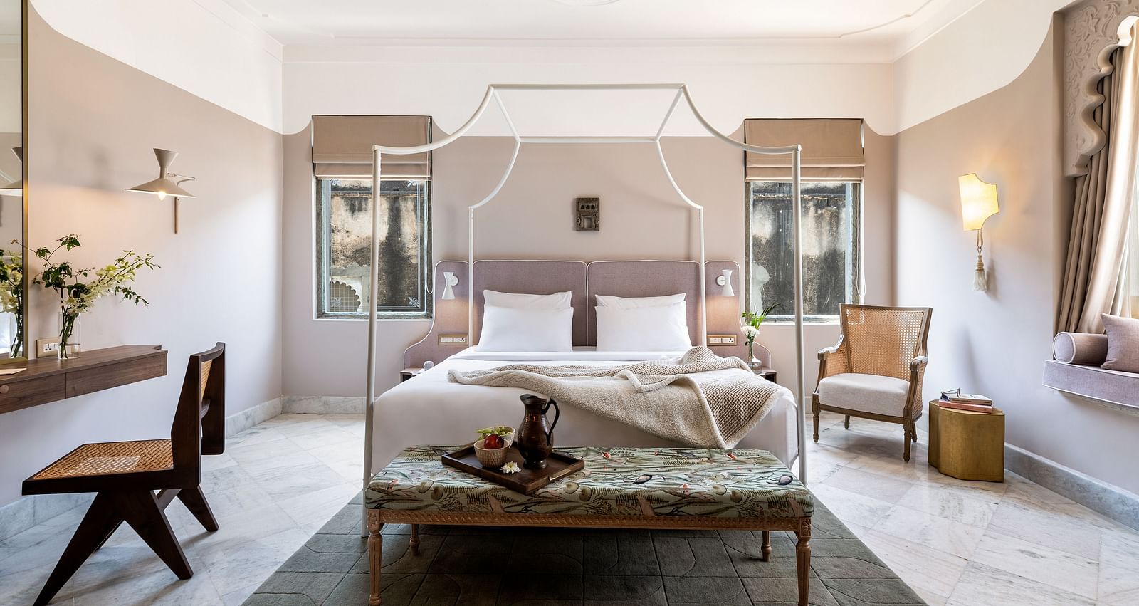 a double bed with a small seating area at the base of the bed inside one of the rooms - Manuscript - Jhilwara Haveli, Udaipur