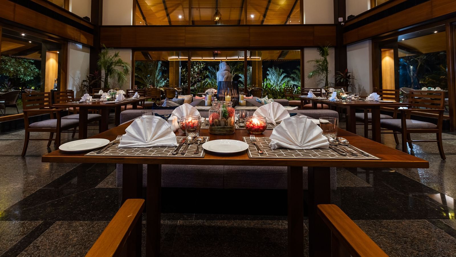 Seating arrangement inside the Restaurant with cutlery on the table in view - Gamyam Resort