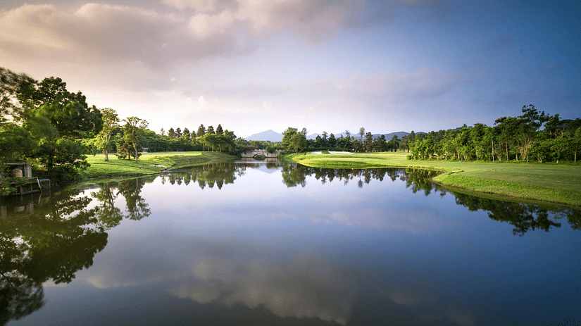 Scenic view of a lake with trees lining the shore under a partly cloudy sky.