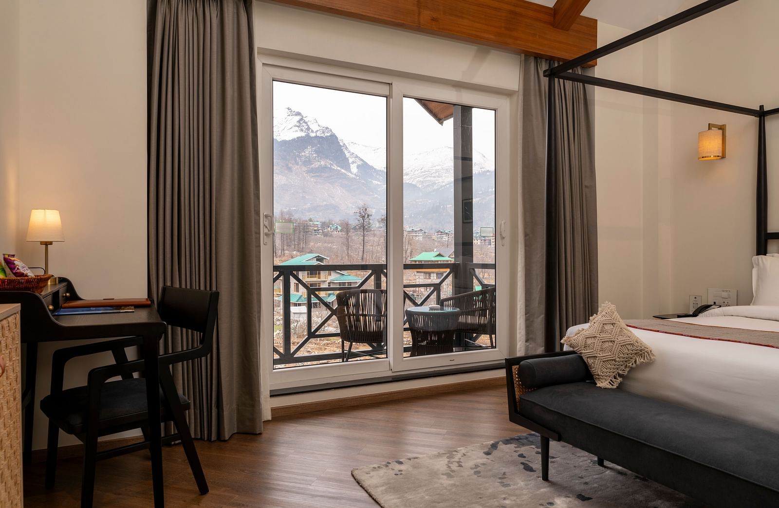 Bedroom with a four-poster bed, desk, and mountain view at Nivasana Manali.