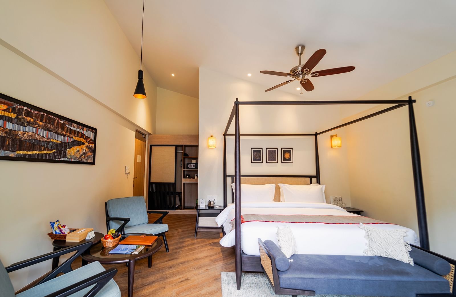 Bedroom with a four-poster bed, seating, and a fan at Nivasana Manali.