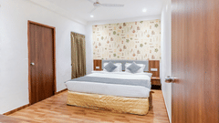 Suite at Pride Elite Wellness Resort Becharaji, Gujarat featuring a plush bed on wooden furnished floor with two nightstands on both sides