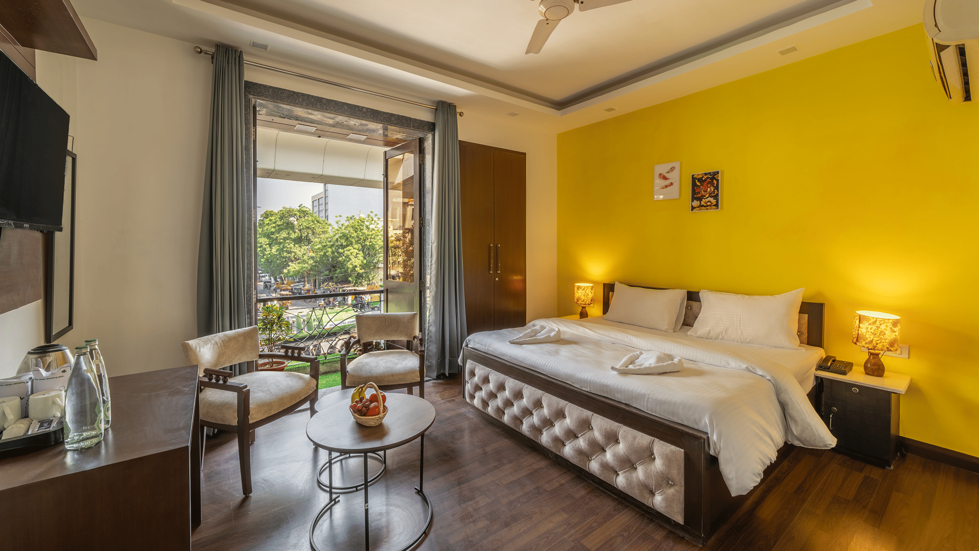 Bedroom of Lime Tree Hotels & Service Apartment Private Limited featuring a yellow accent wall, a round table, and bedside lamps.