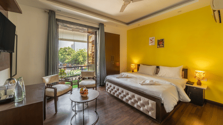 Bedroom of Lime Tree Hotels & Service Apartment Private Limited featuring a yellow accent wall, a round table, and bedside lamps.