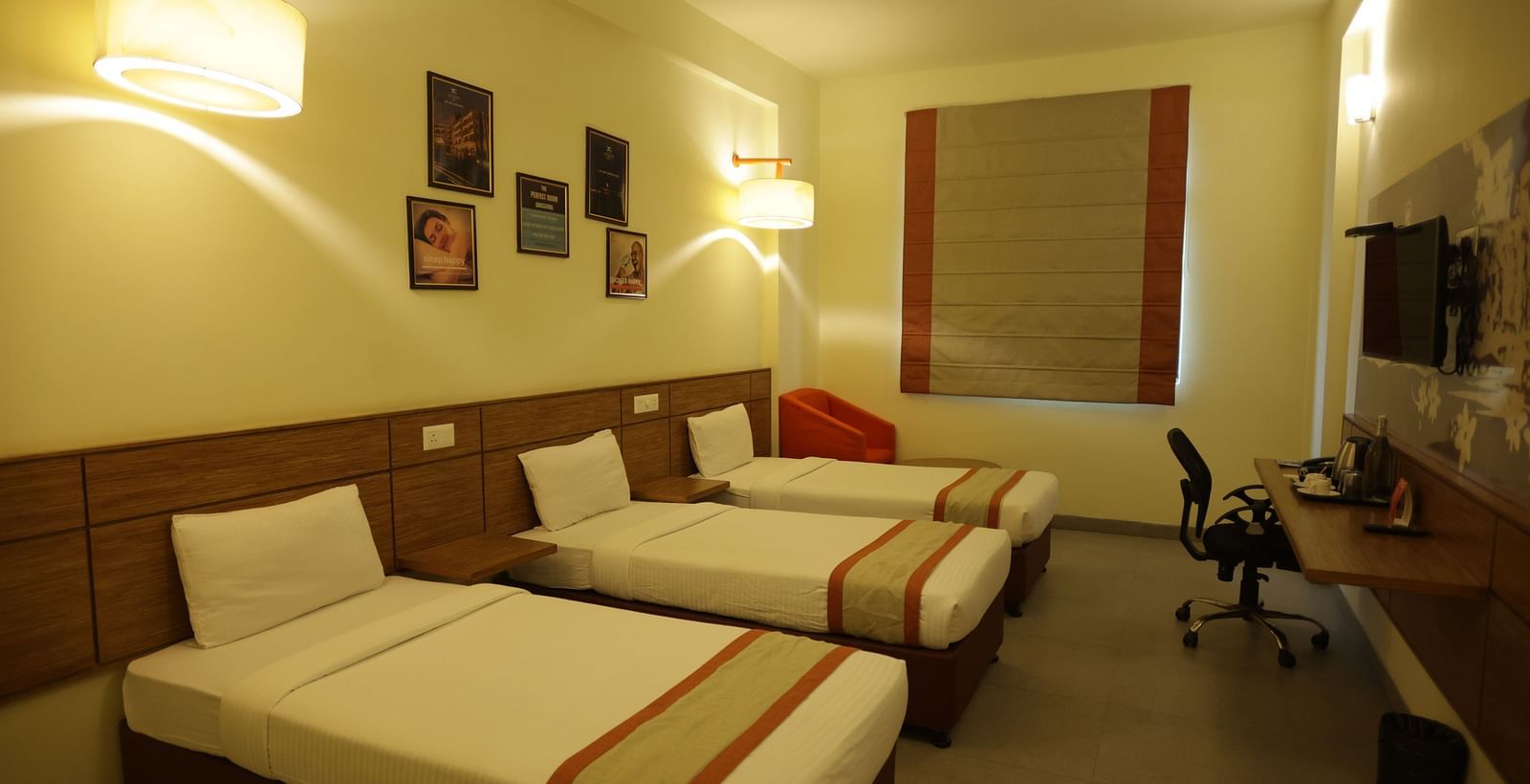 corner view image of the room with three single beds and a work station opposite to it - Max Hotel Jabalpur