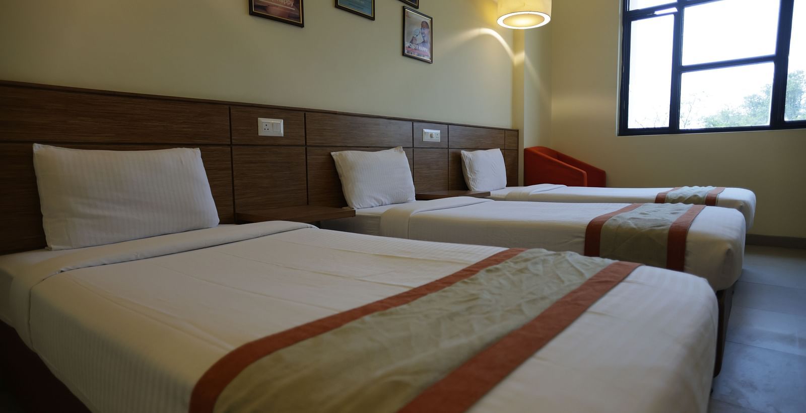 a close up shot of a single bed with the other two beds placed right beside it - Max Hotel Jabalpur
