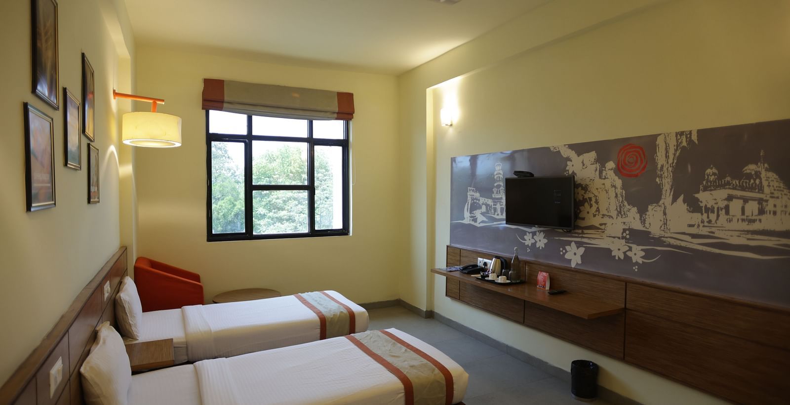 corner view image of a room with three single beds facing towards the wall mounted television - Max Hotel Jabalpur