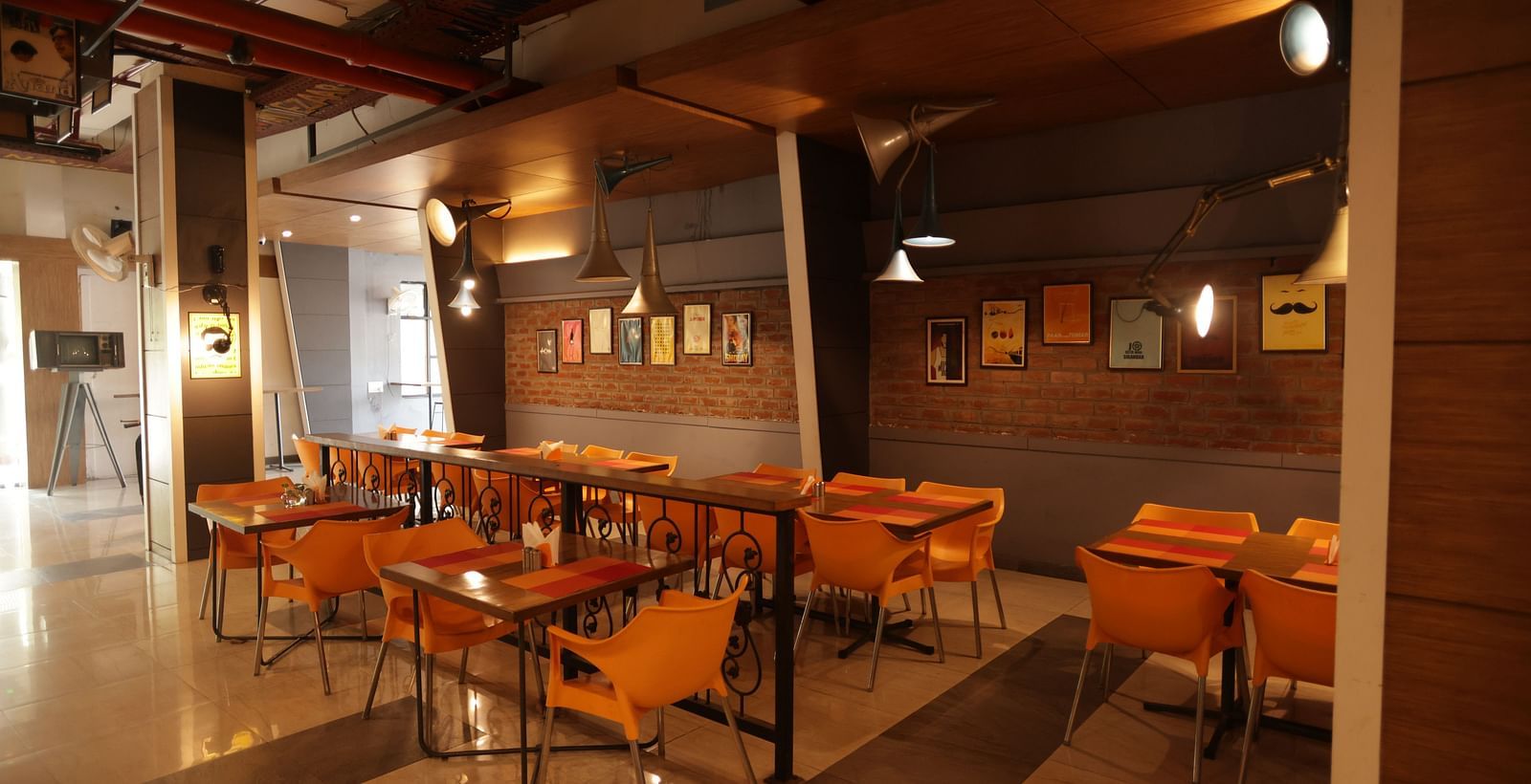 corner view image of a dimly lit dining area with chairs and tables arranged with chic interiors - Max Hotel, Jabalpur