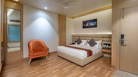 The deluxe room at DLS Hotel Arihant, Haridwar with a bed, bed side tables, a chair, and other room amenities