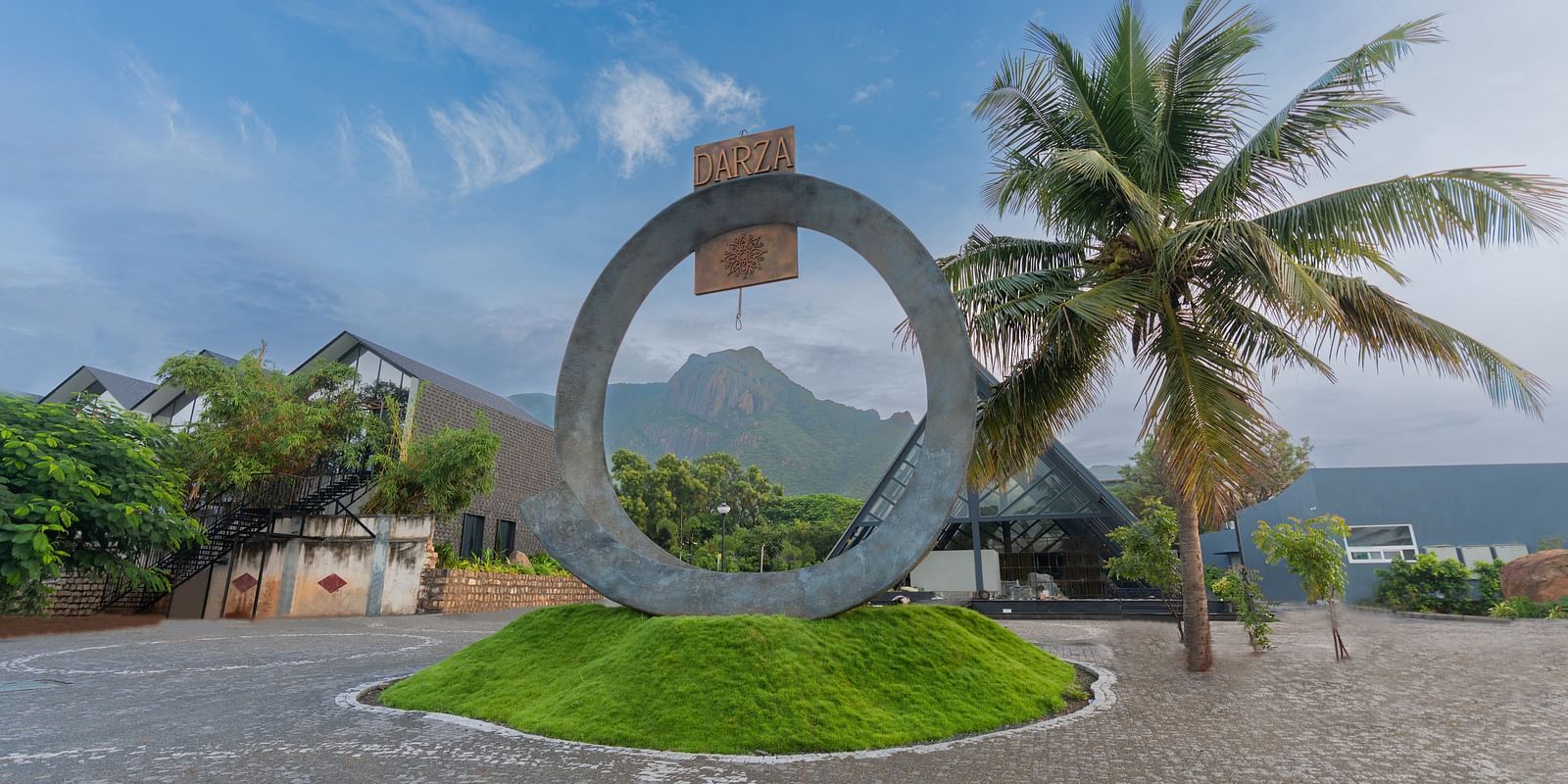 Entrance featuring the logo of Darza Resorts on a ring like structure with clear blue skies in the background.