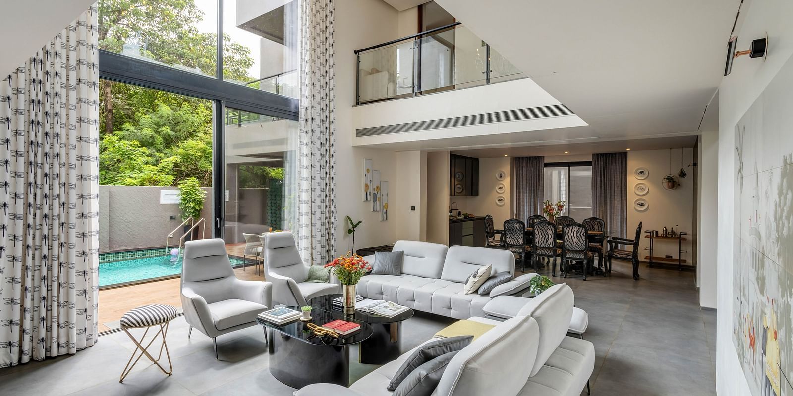 A Corner view of the living room at Lindsay Manor, featuring a sofa, a pool view window, and a dining area beside the living room.