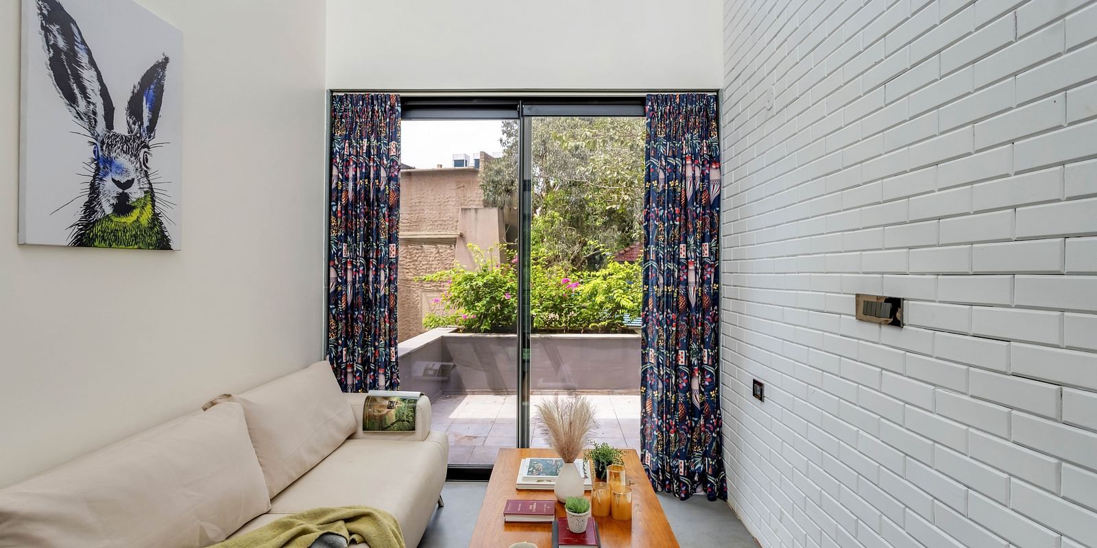 Lounge area at Lindsay Manor with a sofa, frame on the wall tea table, and a glass window offering a pool view.