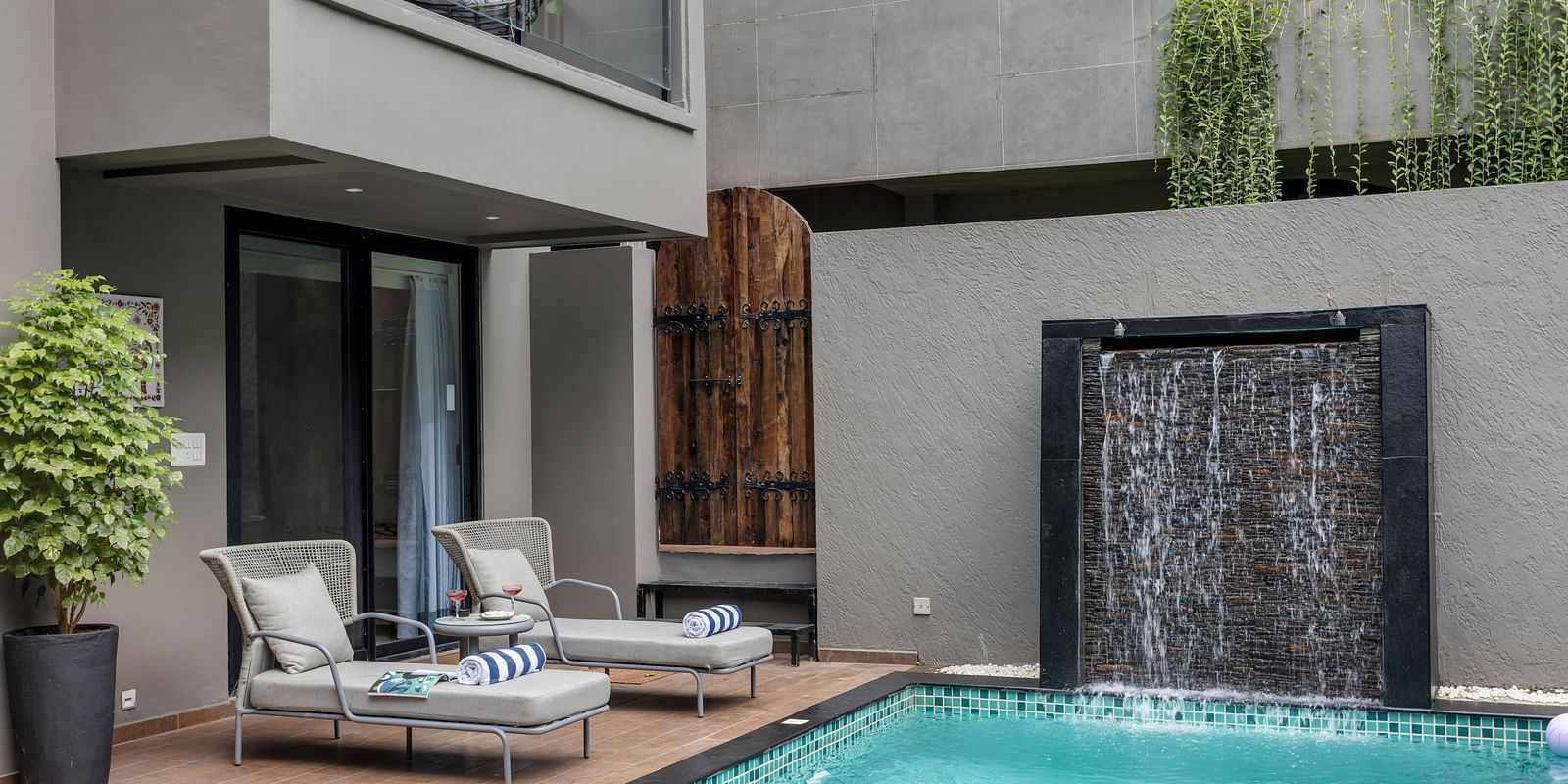 Daytime view of the swimming pool at Lindsay Manor, featuring a lounge bed beside the pool and water flowing through an opening.