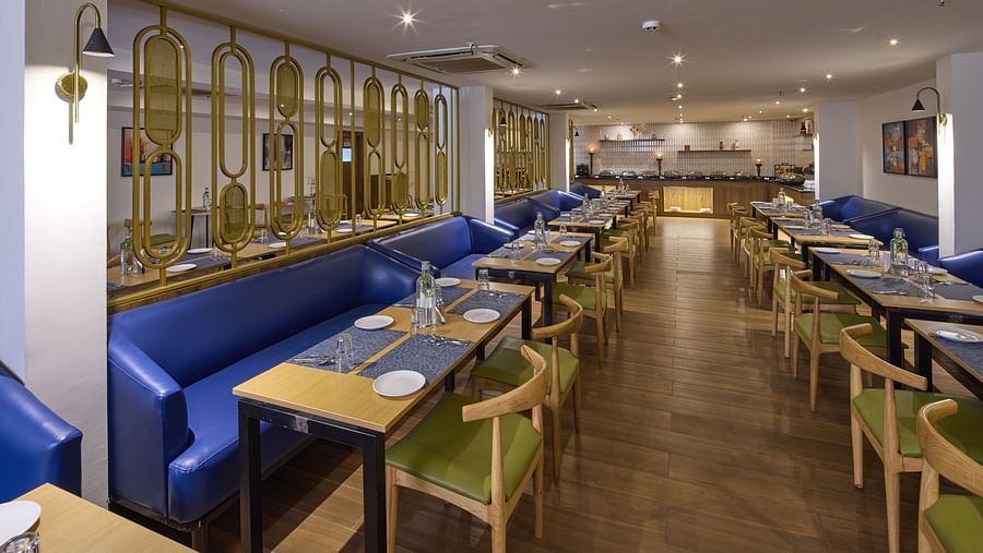 A dining area with blue couches and upholstered chairs placed around glass tables - Grand Continent, Brookefield