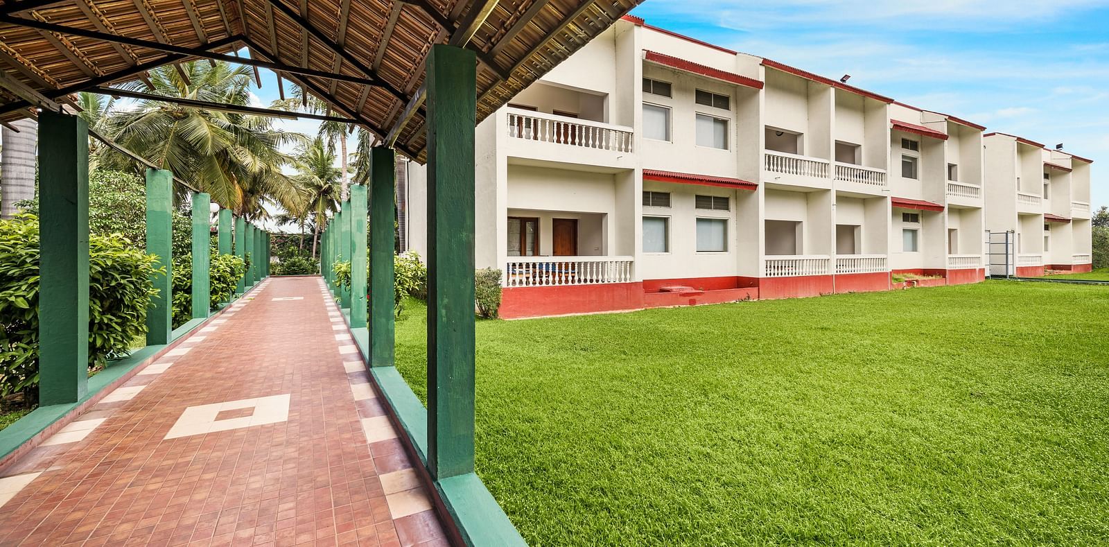 A facade image of the lawn with a shed and the hotel in the background - GReaT Trails River View Resort Thanjavur By GRT Hotels