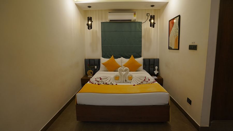 A well-lit bedroom featuring a double bed with a portrait on the wall at Hotel Kyzen Smartstays – Smart, Reliable, Kyzen