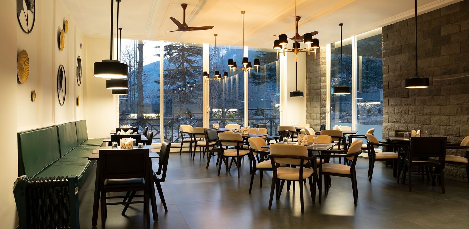Bright dining area with floor-to-ceiling windows and elegant seating at Nivasana Manali.