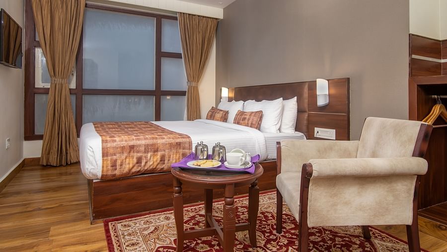 An armchair, a tea table and a double bed in the Deluxe Double room at Hotel Sumitel Vista T.V Tower 