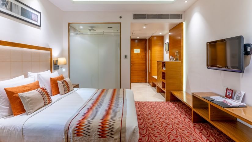 Superior room featuring a plush bed in front of a Tv mounted on the wall and a bathroom with frozen glass