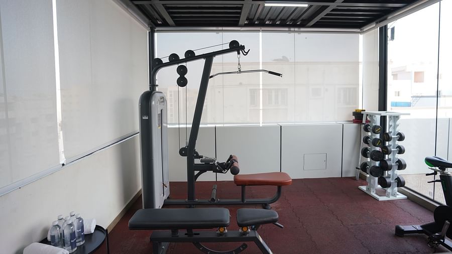 A fully equipped gym with workout benches, a lat pulldown machine, and weights at Hotel Kyzen Smartstays  Smart, Reliable, Kyzen