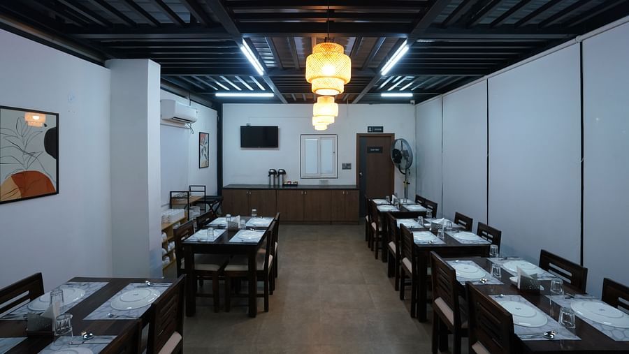 view of the indoor dining area, showing more tables and chairs in a well-lit, minimalist setting at Hotel Kyzen Smartstays – Smart, Reliable, Kyzen