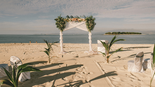 A wedding arch set up at a beach during a sunny day.