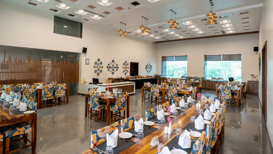 A restaurant at Bamboo Saa Mulberry Resort, Pushkar, offering a buffet setup and spacious seating arrangements and a help desk.