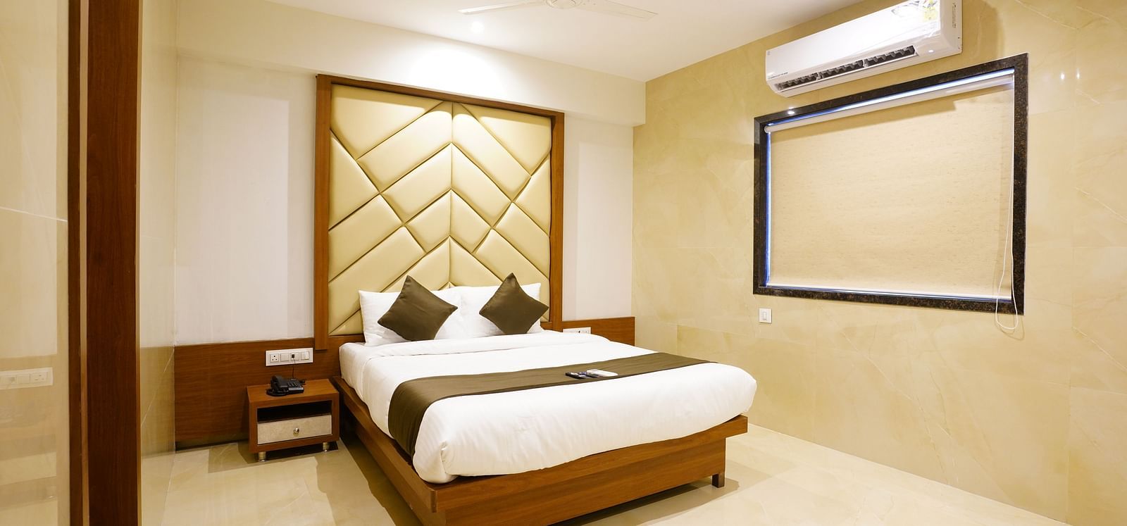 Hotel room with a double bed, decorative headboard, and framed artwork - Shyanu Lords Eco Inn Airoli