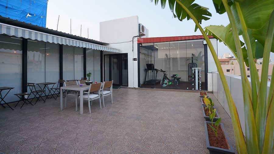 A spacious rooftop dining area with tables and chairs, surrounded by some plants at Hotel Kyzen Smartstays – Smart, Reliable, Kyzen