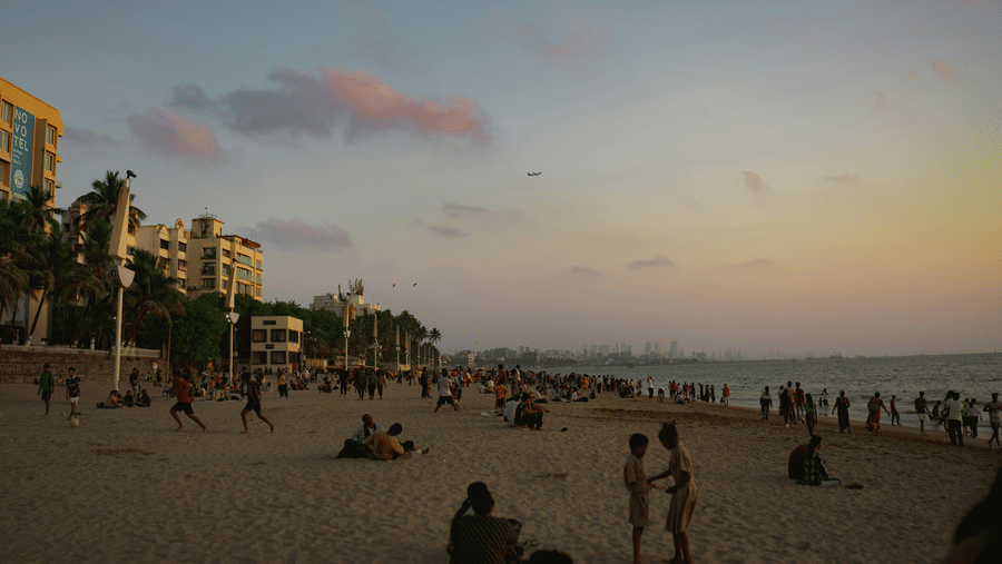 Numerous people walking and looking at the sunset while being on the shoreline of Juhu Beach. This beach is one of the best places for a one-day picnic near Mumbai.