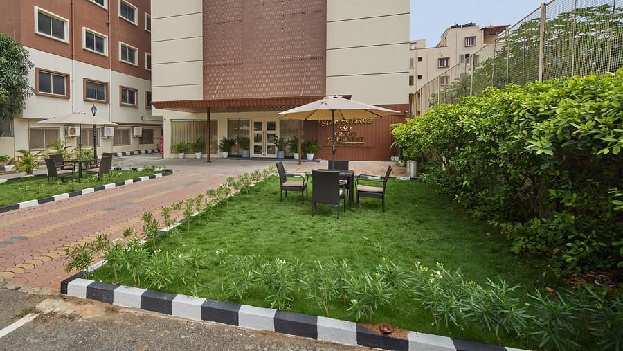 A wide angle view of our outdoor wedding venue in Bangalore with a well-manicured lawn and cosy chairs placed under sun loungers - Grand Continent, Brookefield