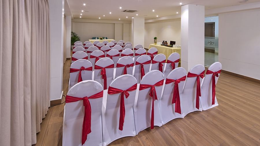 Chairs dressed in white cloth, with vibrant red ribbons tied around the backs, filling our elegant banquet hall - Grand Continent, Brookefield